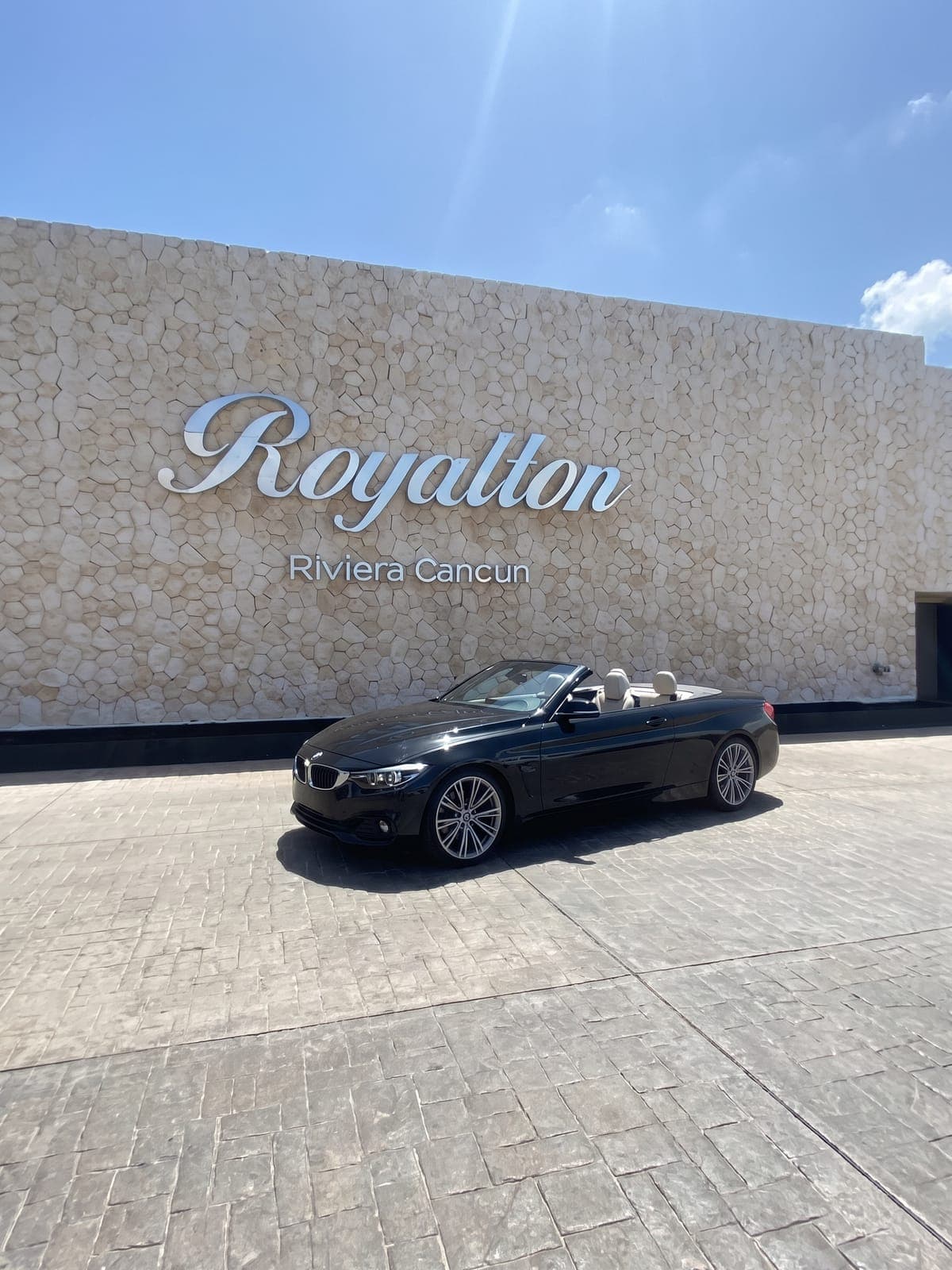 BMW 430i convertible negro frente a la entrada de un resort en la Riviera.