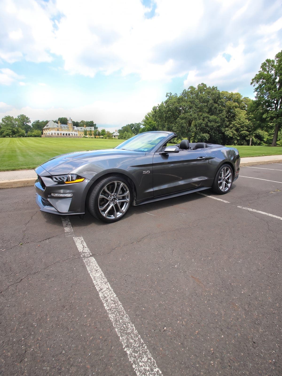 Ford Mustang GT gris descapotable junto al césped de un club.