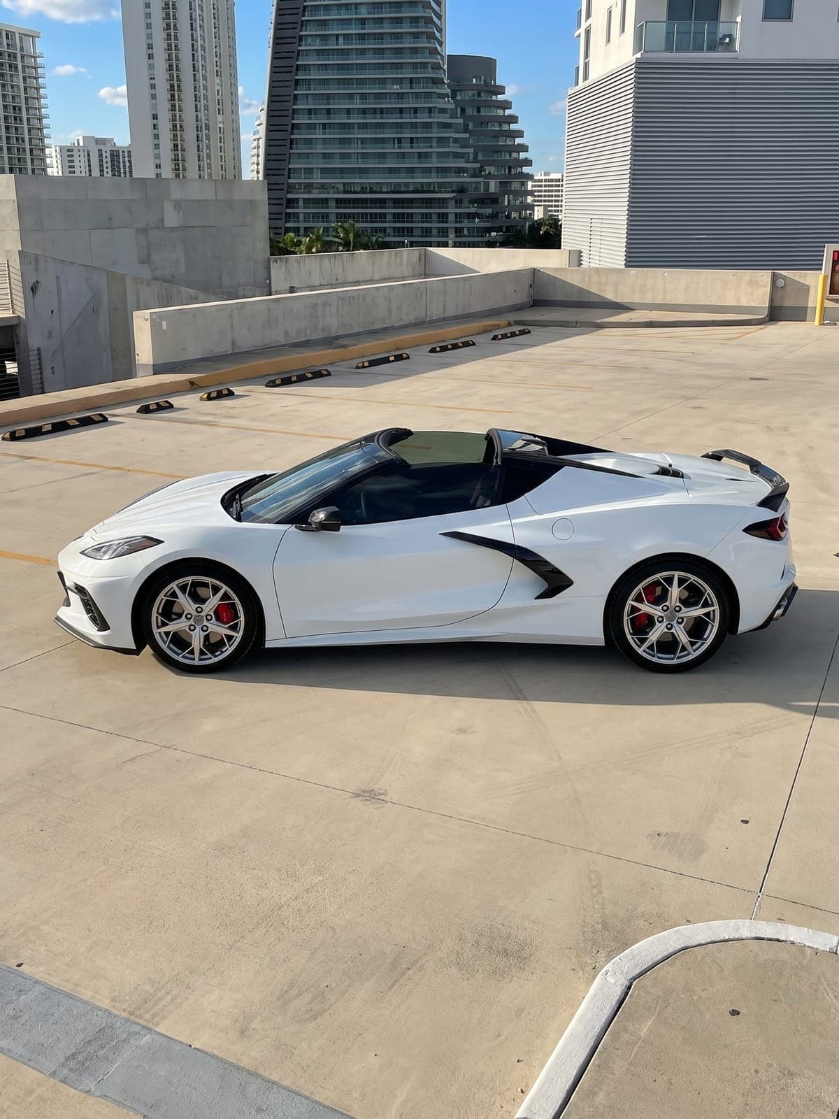 Chevrolet Corvette Stingray blanco frente a torres junto al mar.