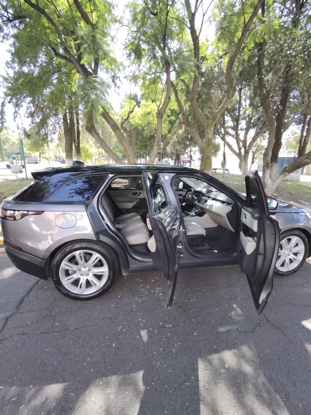 Range Rover Velar gris en una calle arbolada de la zona.