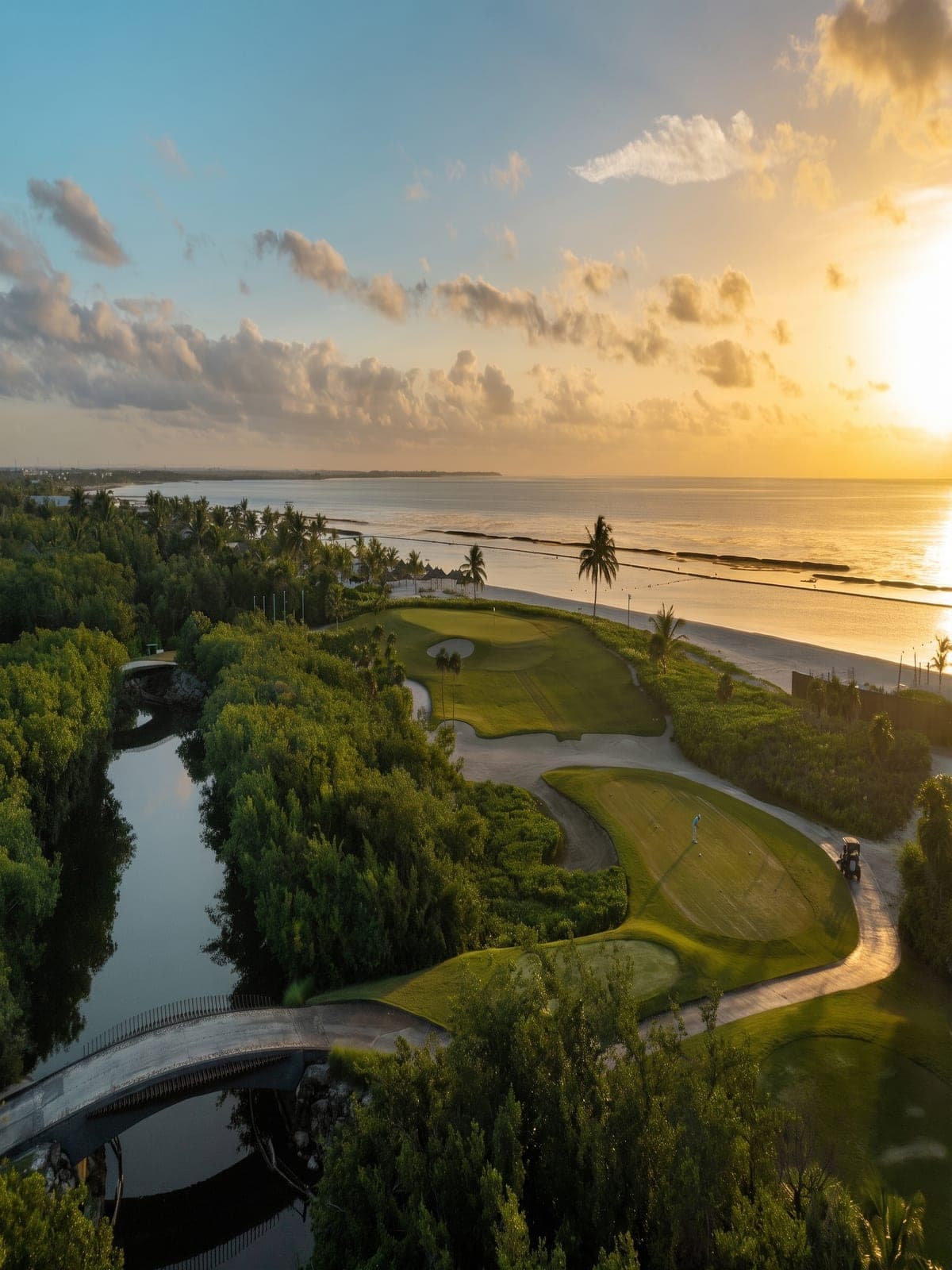 An aerial view of the El Camaleón golf course at sunset, beside the sea and the mangrove.