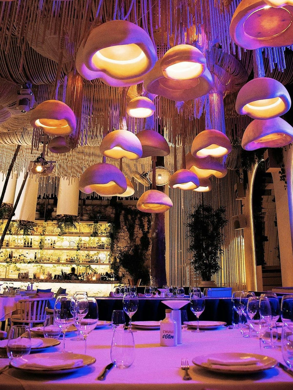 Bagatelle, cocina mediterránea en Tulum: interior con lámparas de colores y mesas montadas.