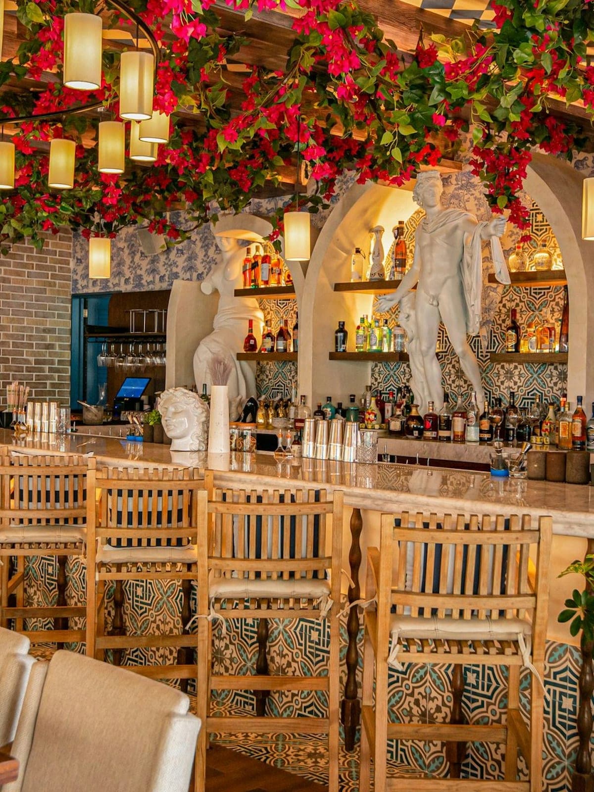 Nicoletta, cocina italiana en Playa del Carmen: interior con arcos, flores colgantes y barra.