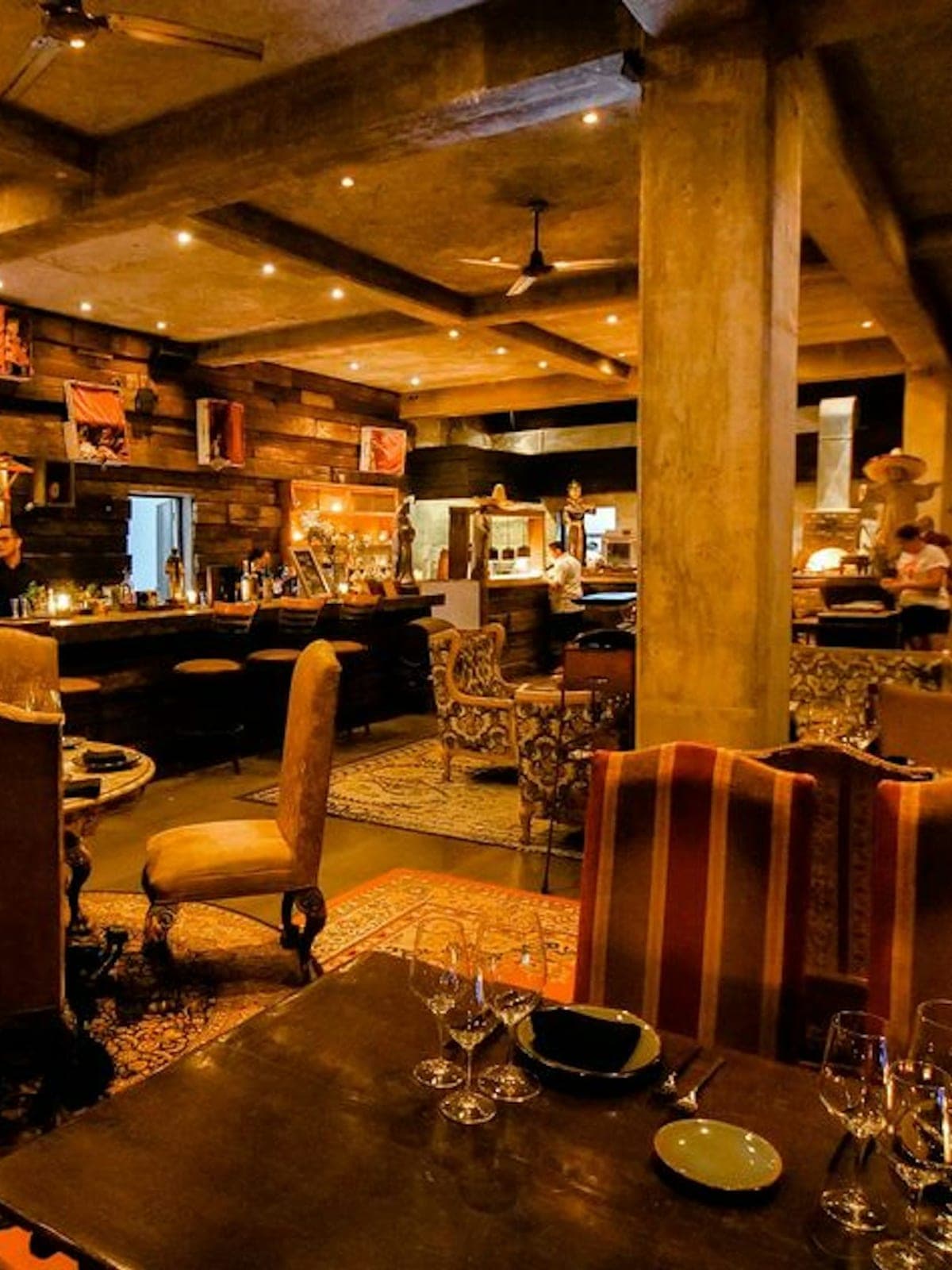 Casa Malca, cocina de autor en Tulum: bar interior cálido en madera y terciopelo.