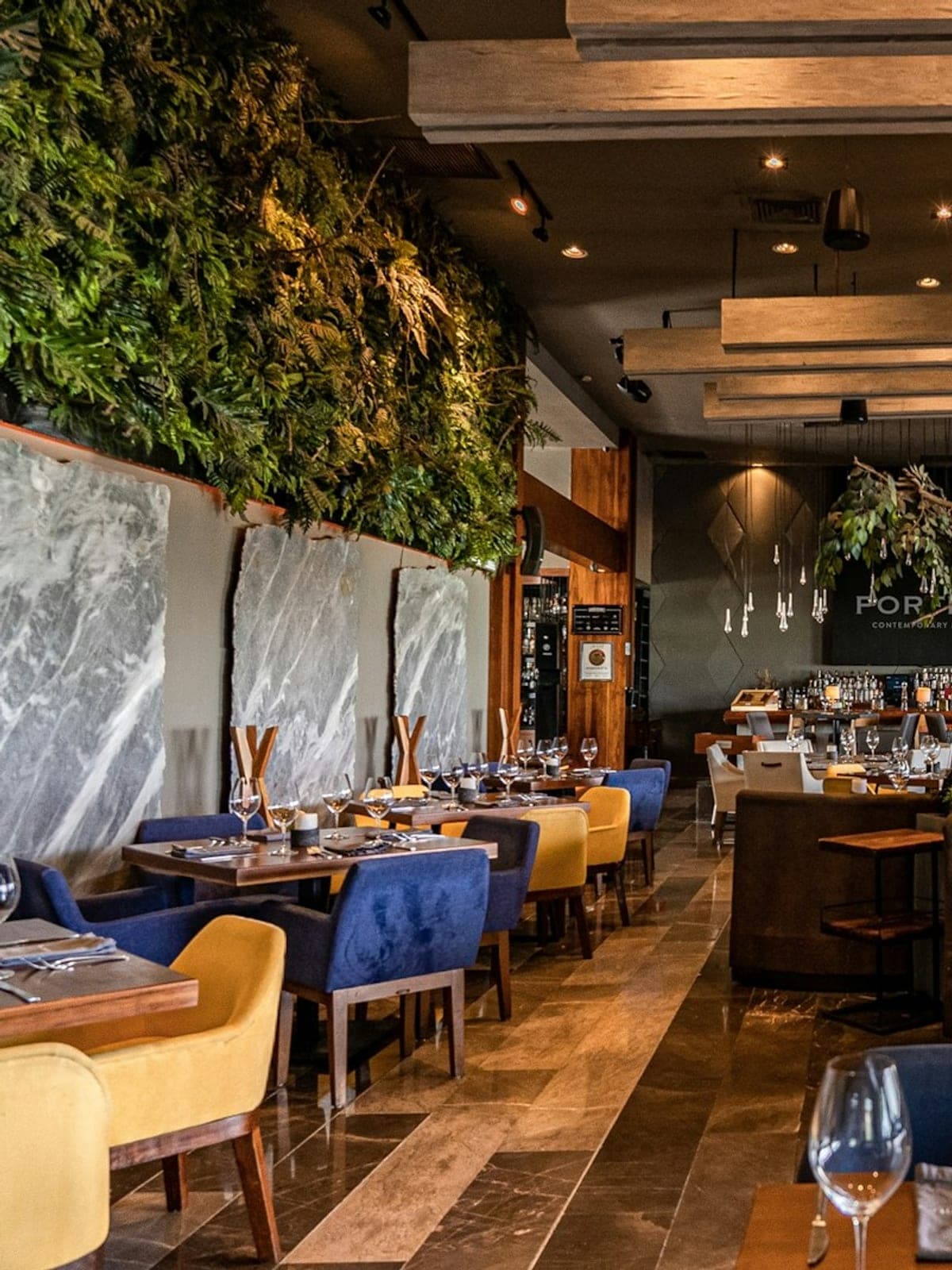 Porfirio's, cocina mexicana en Cancún: interior con sillones azules y muro de vegetación.