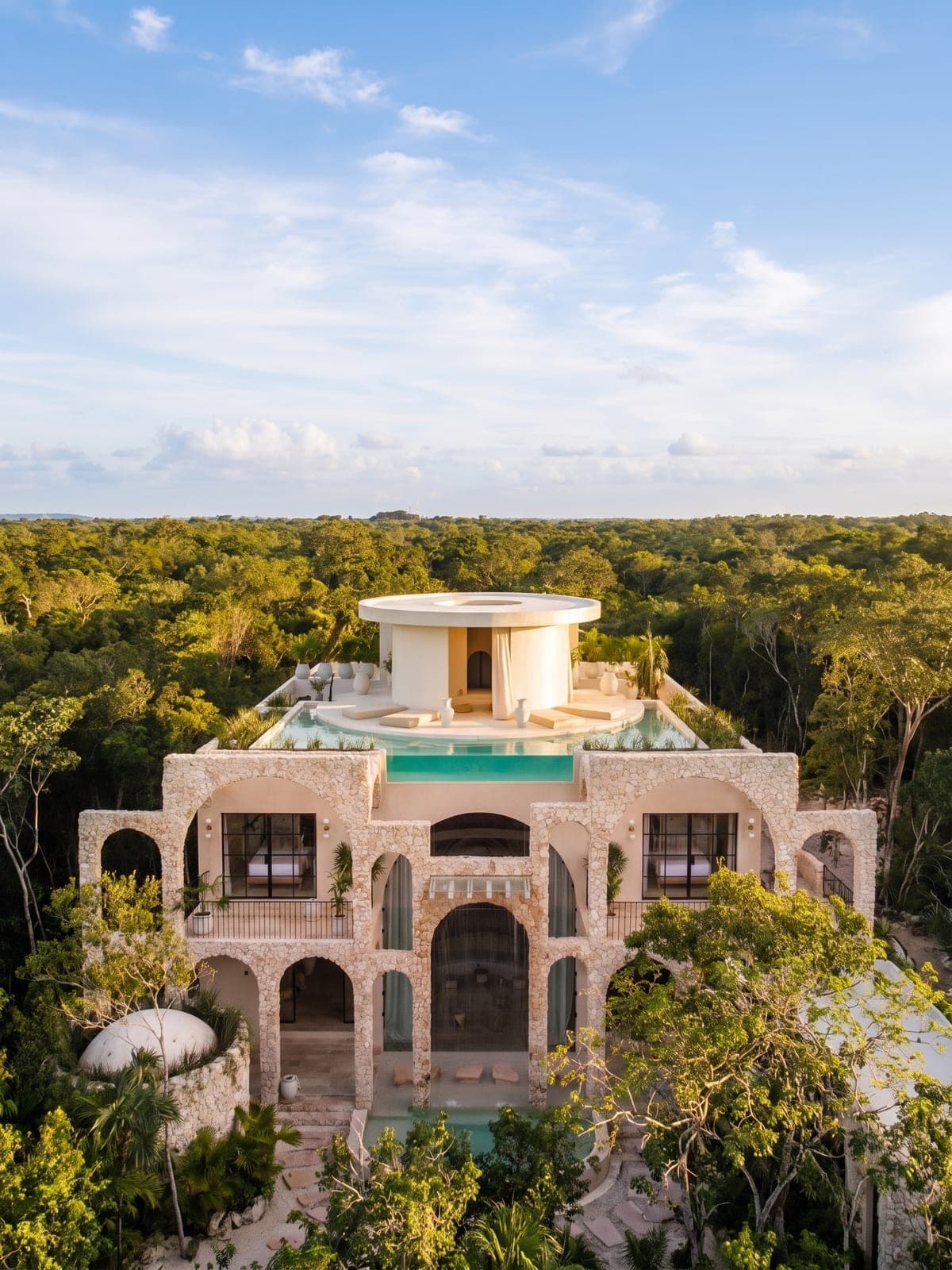 Casa Arka, a stone residence in Tulum, Riviera Maya: quarry-stone arches and a rooftop pool ringed by jungle.