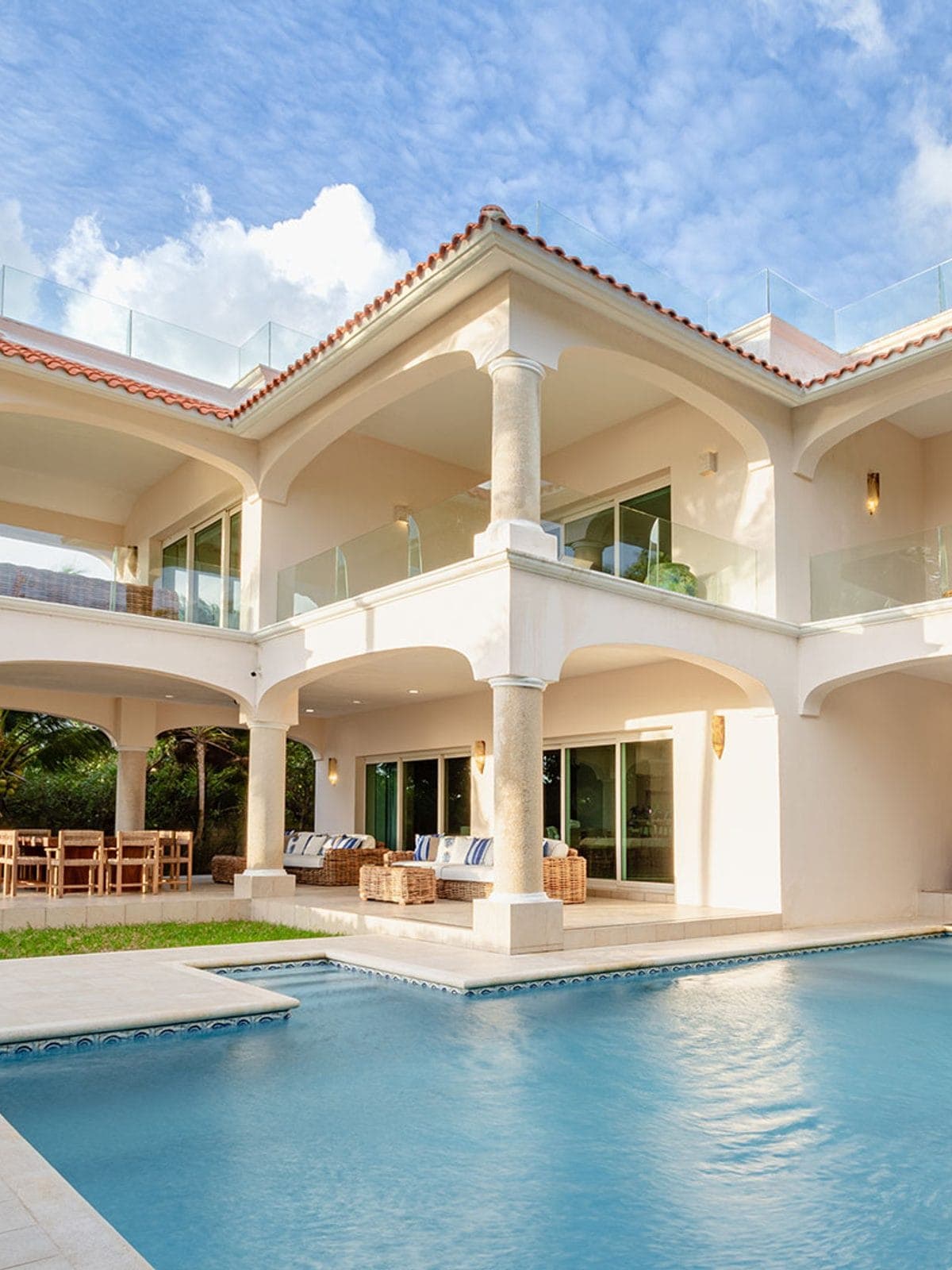 Villa blanca de dos niveles con alberca y terraza.