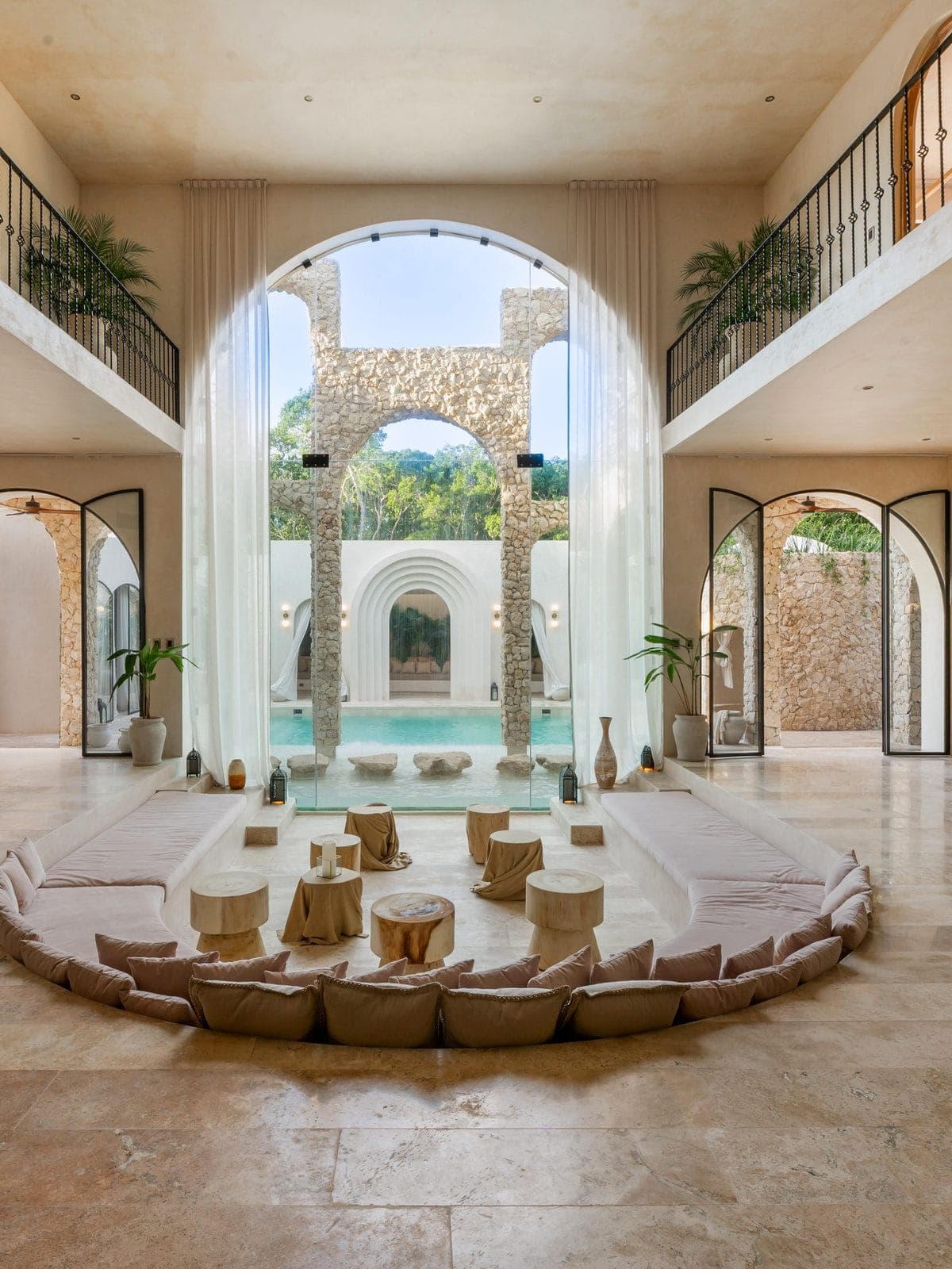 Interior de doble altura con arcos de piedra y sala baja.