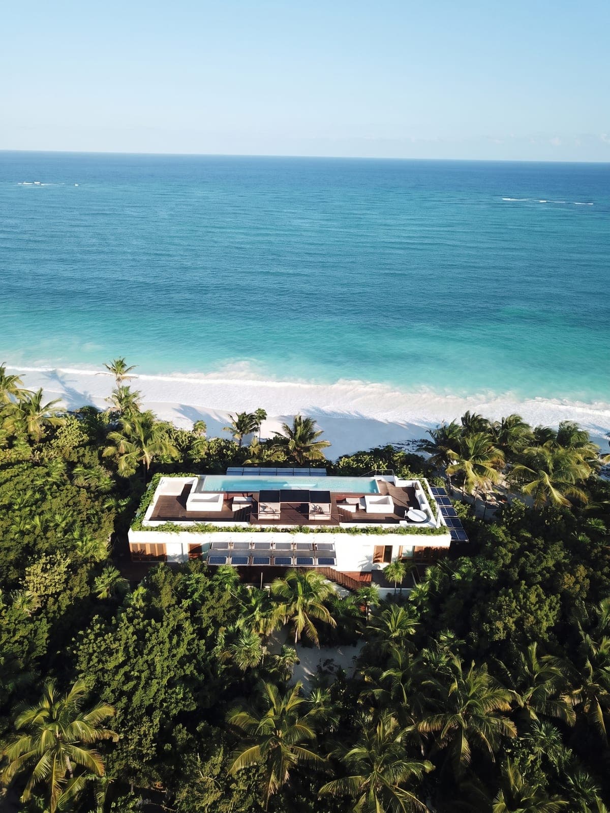 Villa Na'iik, an oceanfront villa in Sian Ka'an, Riviera Maya: a modern house with a rooftop pool above a turquoise beach.