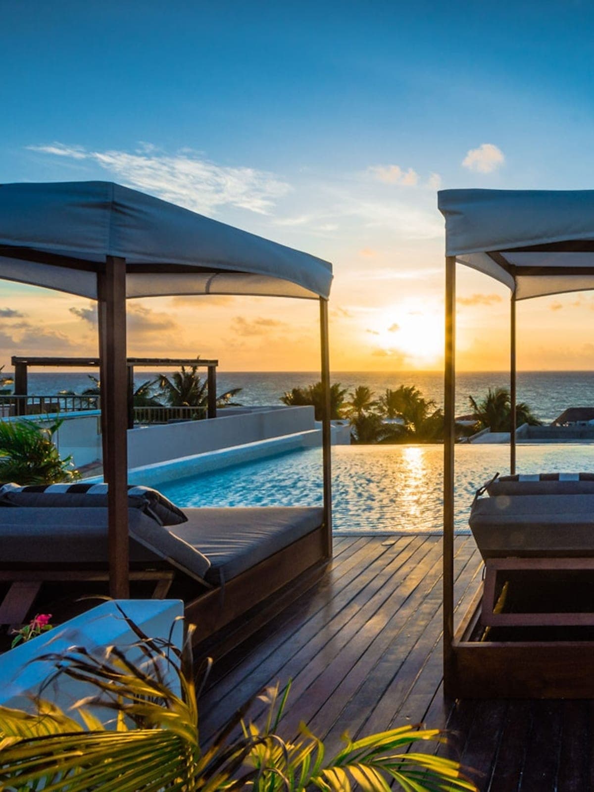 Alta Vista, an oceanfront villa in Playa del Carmen, Riviera Maya: a rooftop with loungers and a pool facing the sea at sunset.