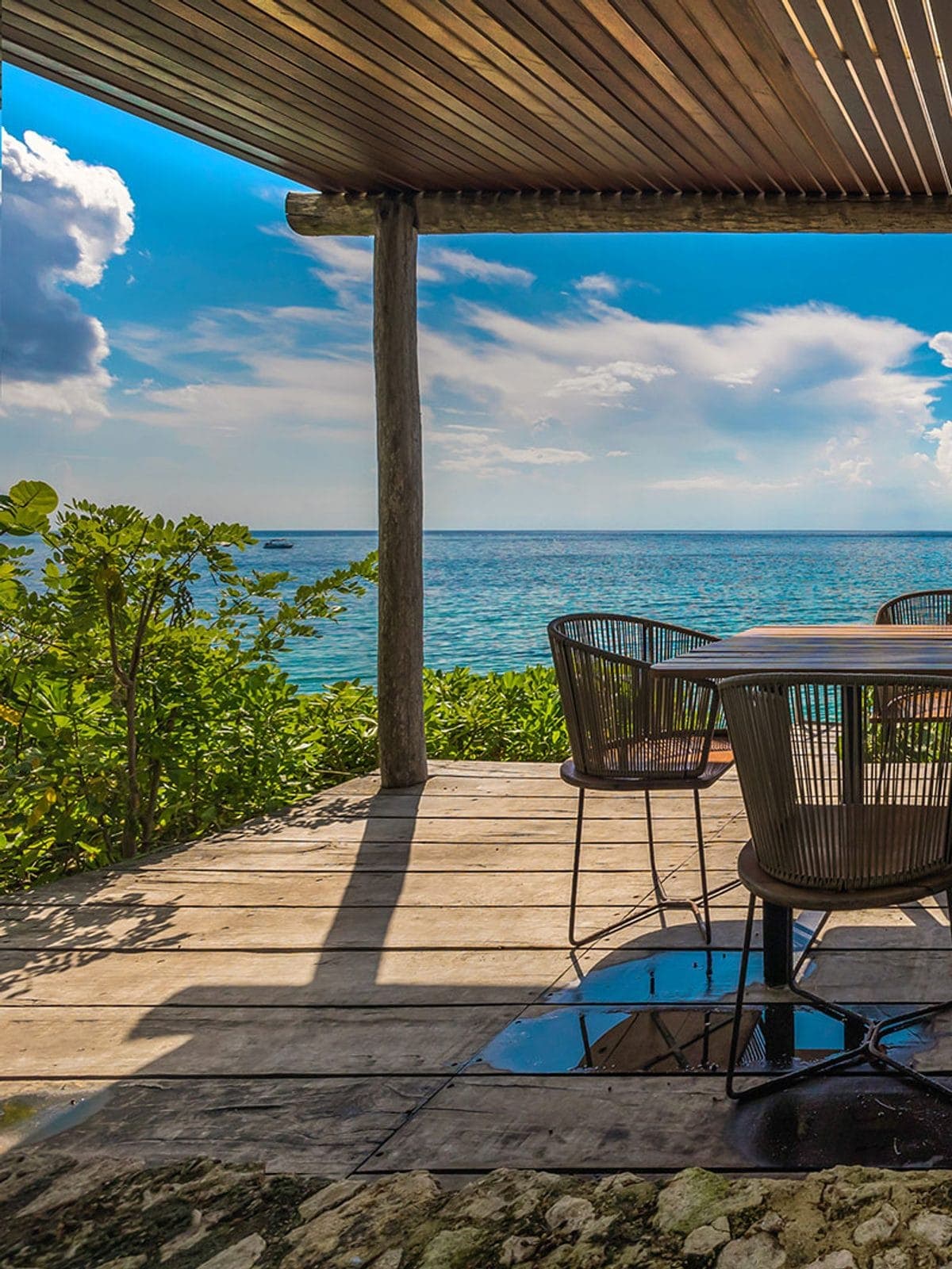 Terraza comedor bajo palapa abierta al mar.