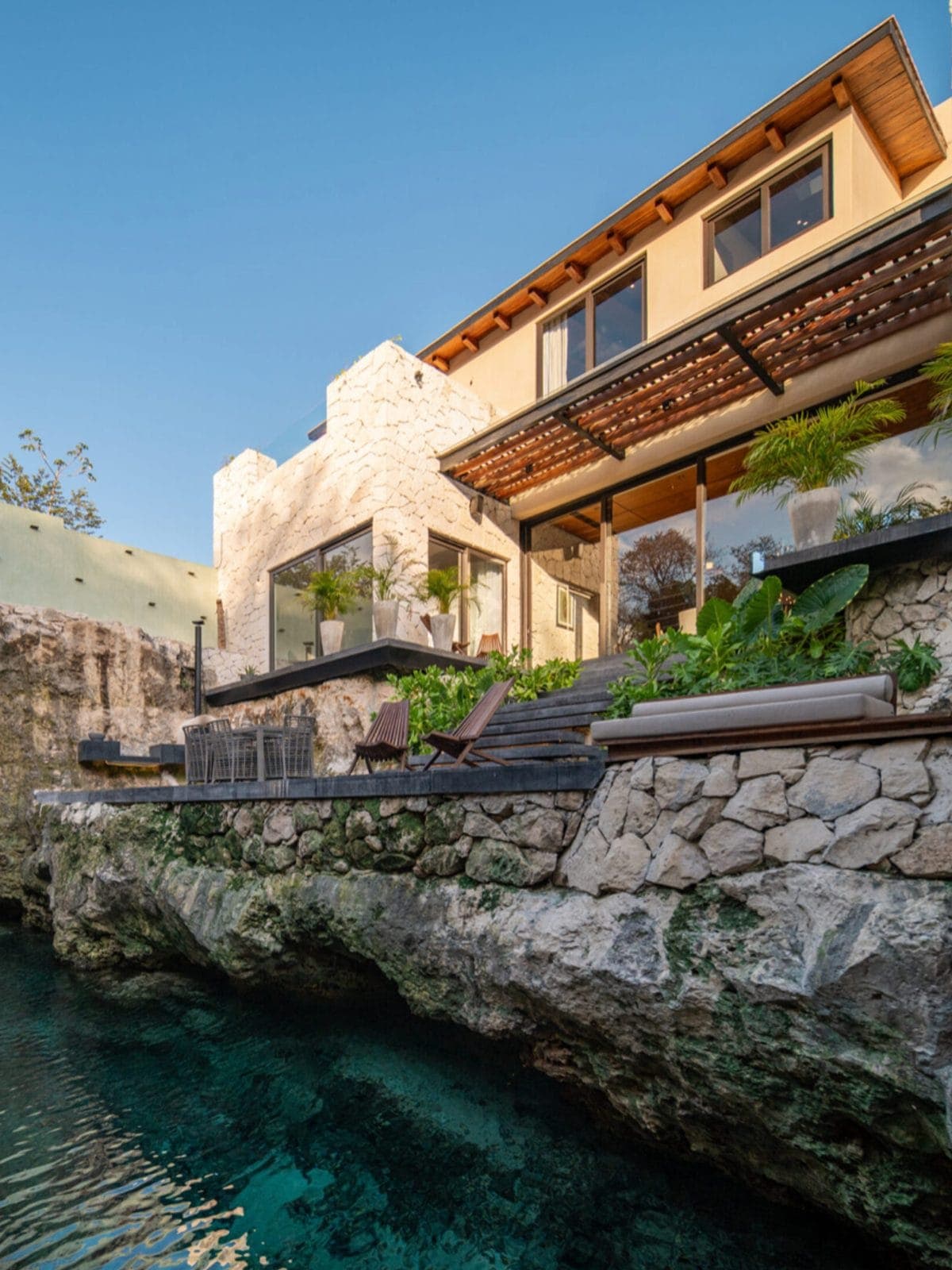 Villa de piedra junto a una caleta de agua turquesa.