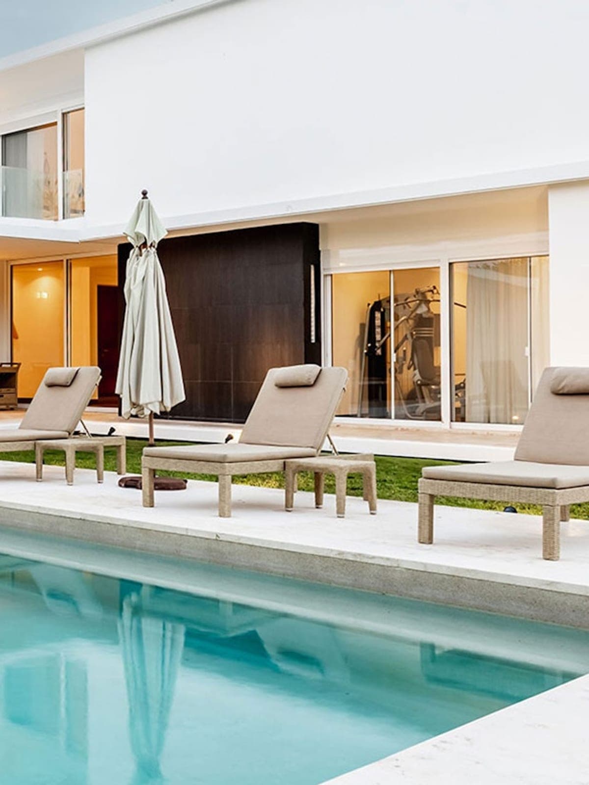 Casa Marazul, a private residence in Cancún, Riviera Maya: a lit modern villa with a pool and loungers at dusk.