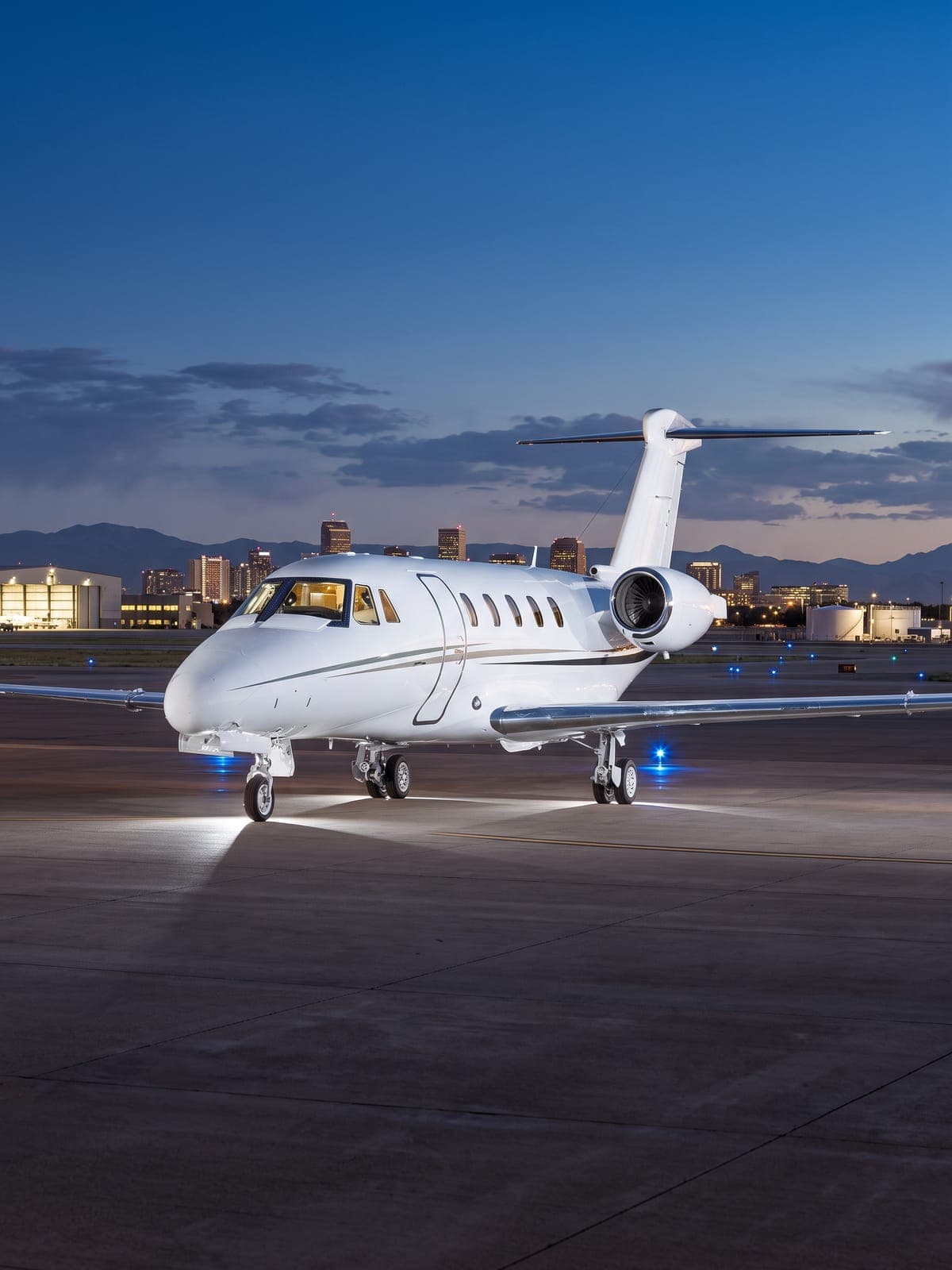 Jet Cessna Citation 650 en plataforma al anochecer con la ciudad al fondo.