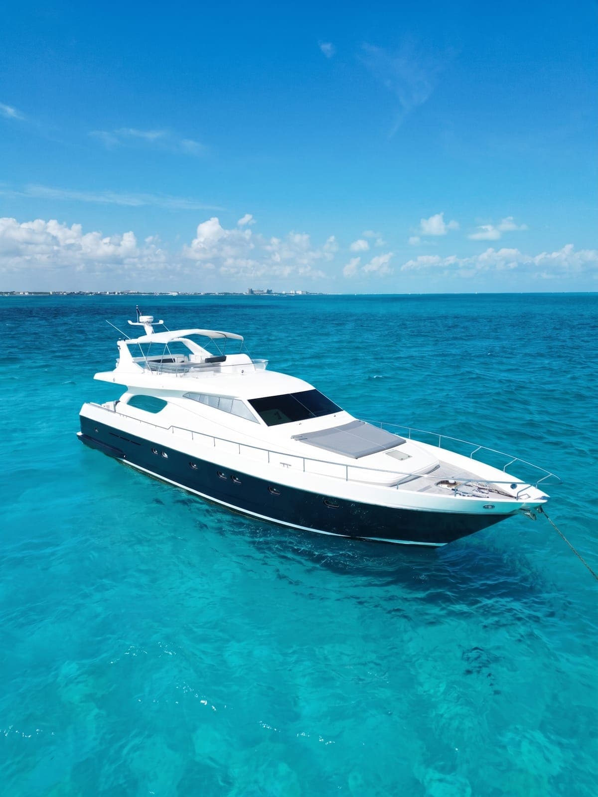 Yate a motor Ferretti fondeado sobre agua turquesa.