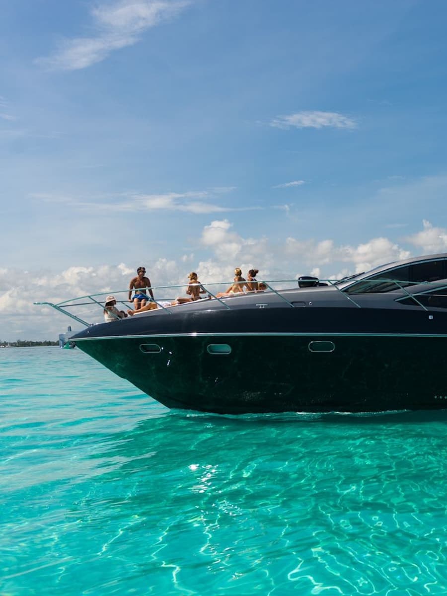 Sunseeker 64, yate deportivo de casco negro navegando sobre el Caribe turquesa rumbo a Isla Mujeres, Cancún.